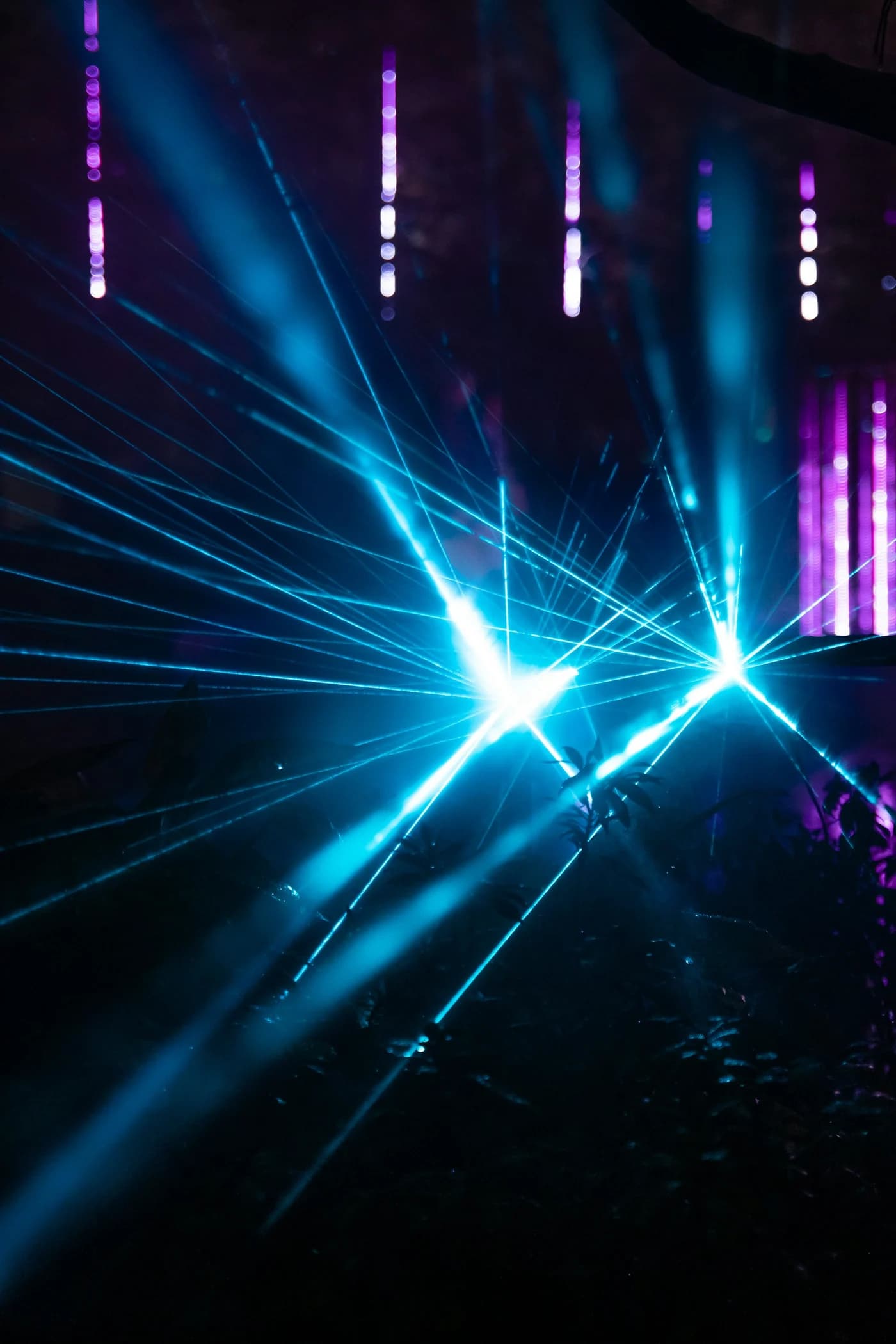 Blue and violet laser light crossing a dark installation space